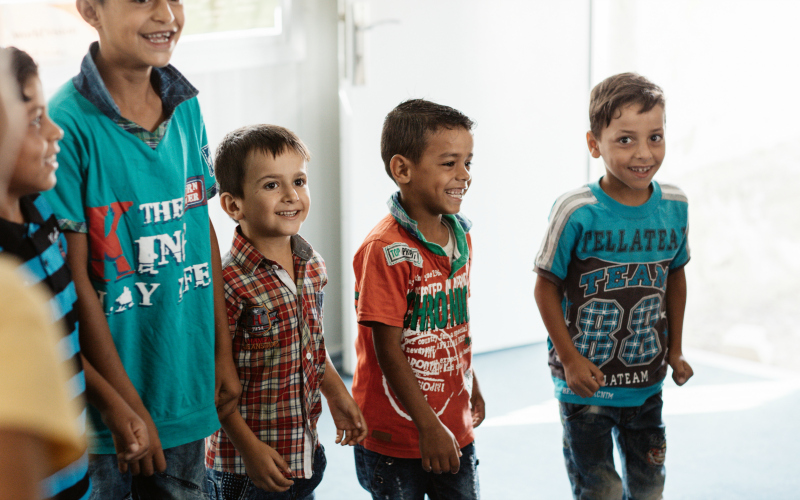 Syrian refugee boys in a circle smiling.