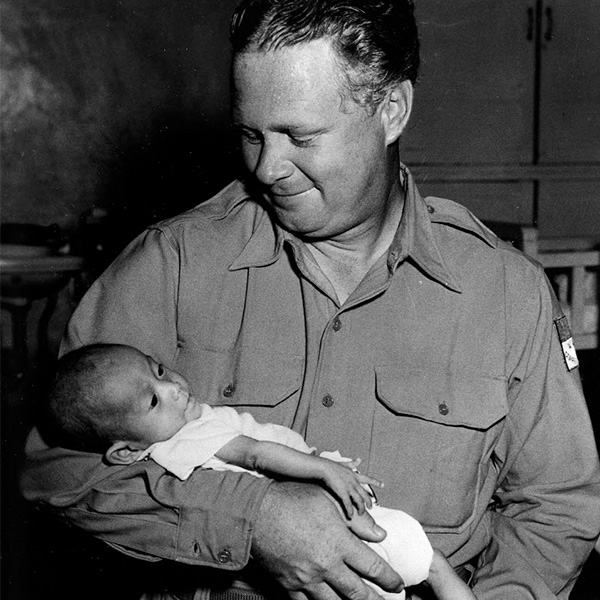 Bob Pierce, fondateur de la charité chrétienne World Vision, tenant un bébé dans ses bras.