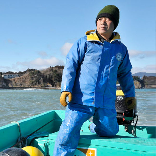 Un homme dirige un bateau avec un logo de Vision Mondiale dessus.