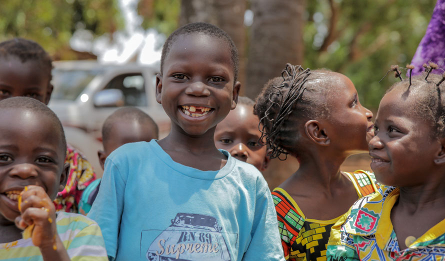 Un garçon portant un t-shirt bleu esquisse un grand sourire.