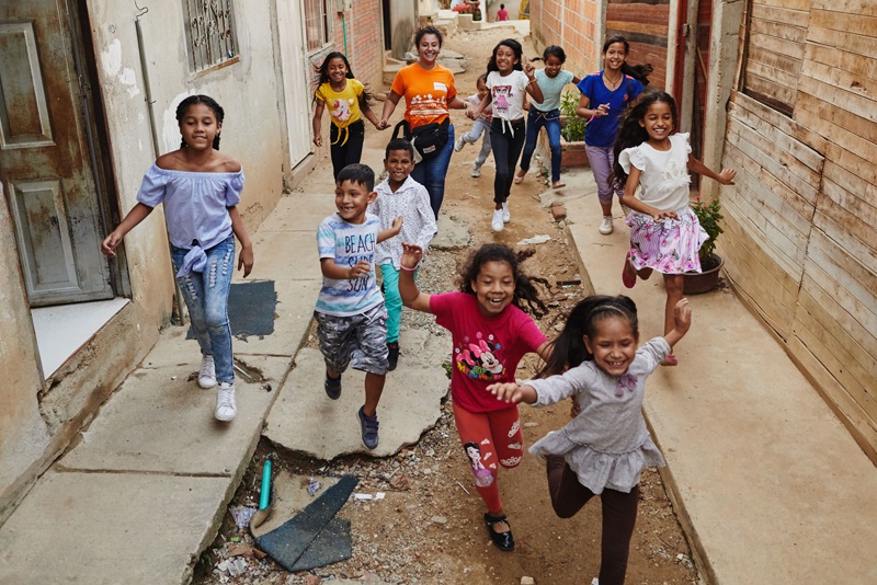 Des enfants d’âges divers courent dans une ruelle.