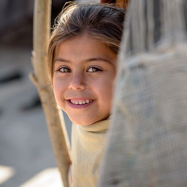 Un enfant parrainé souriant derrière un morceau de tissu.