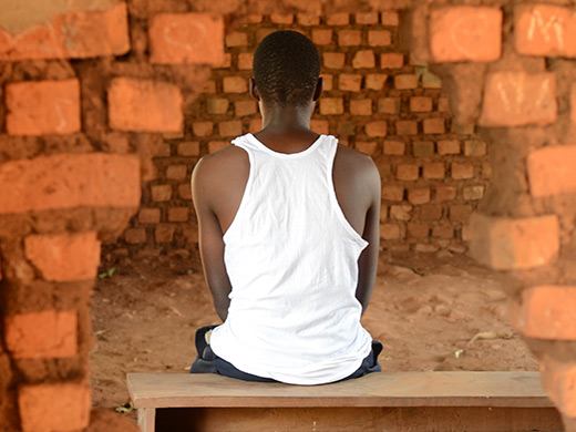 Yuda, 17 ans, est assis sur un banc regardant à travers un trou dans le mur.