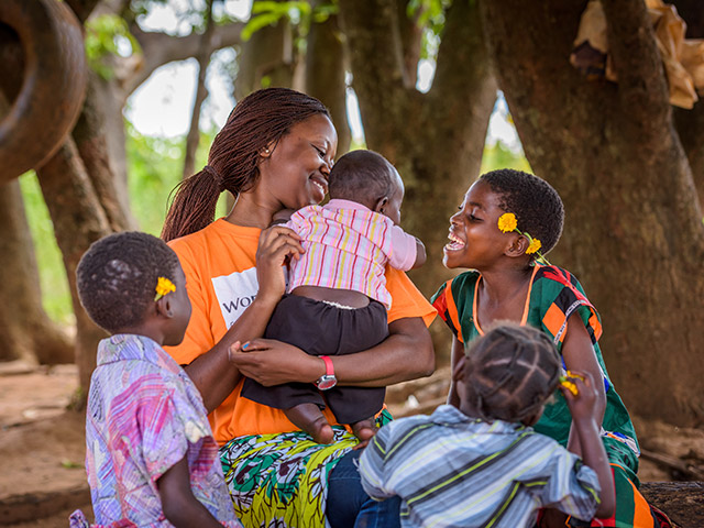 Un groupe d’enfants et une femme avec un bébé dans les bras.