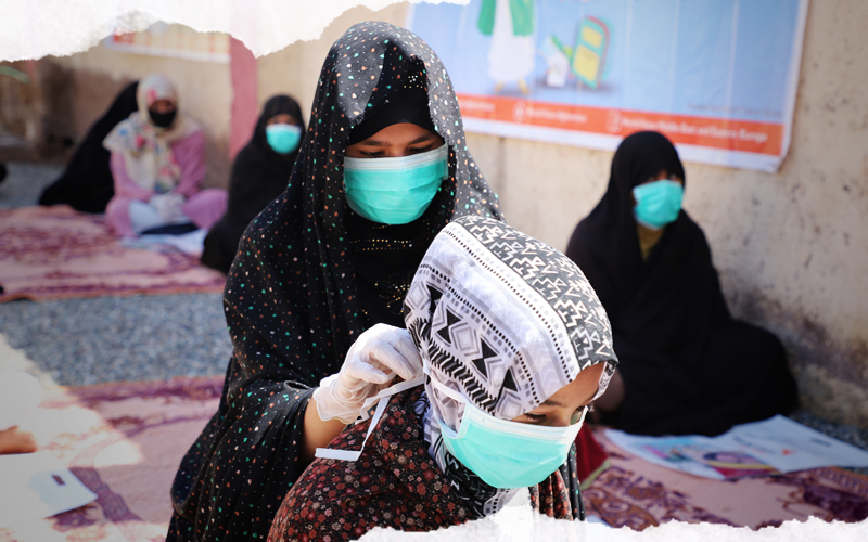 En Afghanistan, Arifa, 12 ans, aide son amie à mettre son masque facial.