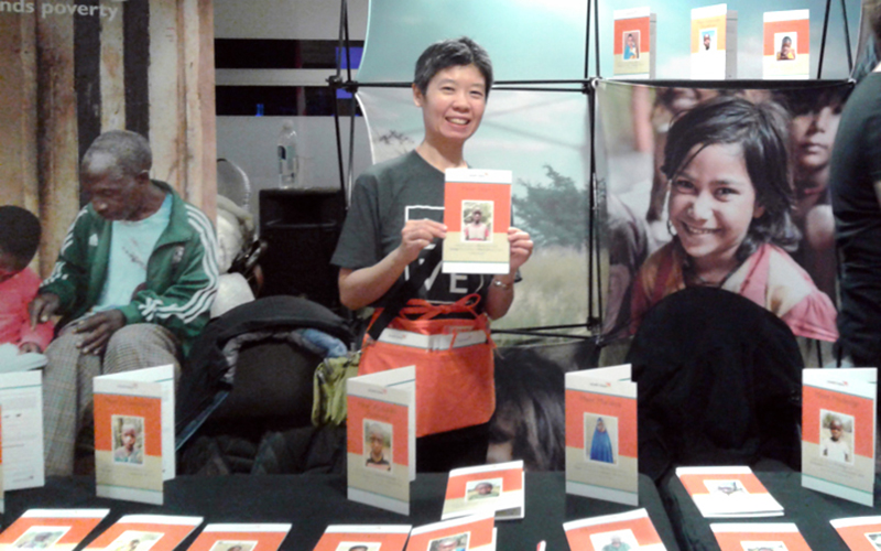 A woman stands at a table holding a photo of a child