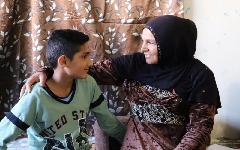 Assis dans leur maison au Liban, un garçon et sa mère se regardent avec amour.