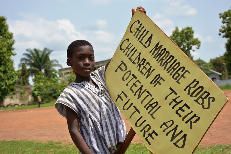 Un enfant tient une pancarte où l’on peut lire : « Le mariage d’enfants vole aux enfants leur potentiel et leur avenir. »