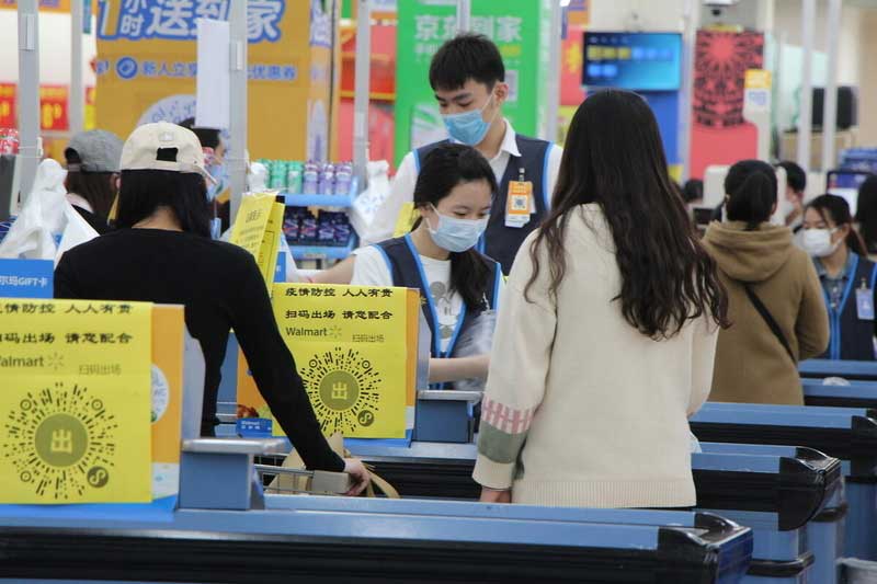 Quatre personnes portant des masques devant la caisse d’une épicerie en Chine.