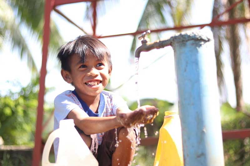 Un petit garçon des Philippines sourit en se lavant les mains