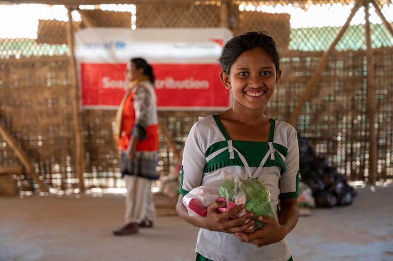 Une fille réfugiée rohingya tenant un sac en plastique avec des pains de savon.