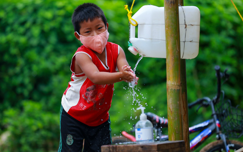 Un jeune garçon au Myanmar se lave les mains avec un tippy-tap