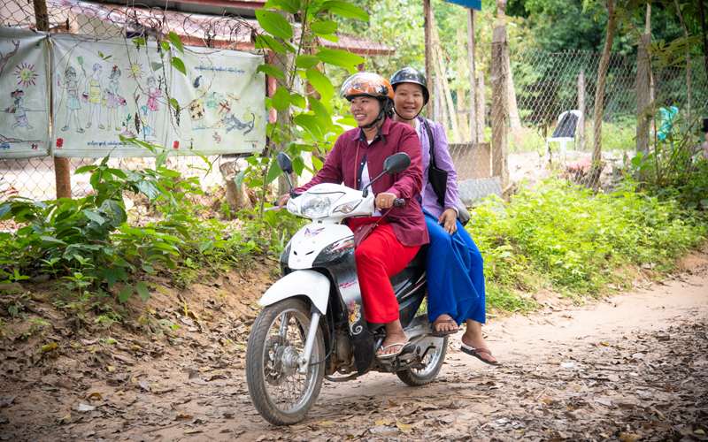 Deux femmes sur une motocyclette au Myanmar sourient.