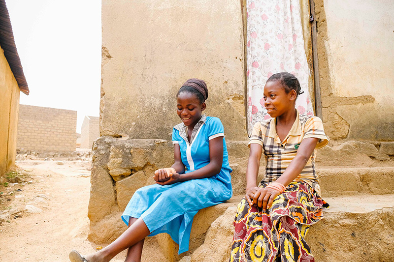 Deux jeunes filles sont assises sur des marches dans un camp de déplacés internes.