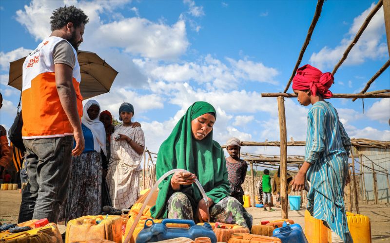 A mom fills up a water container with clean water for her children.