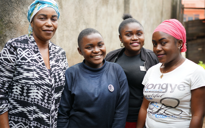 Une femme congolaise et ses trois filles regardent la caméra et sourient.