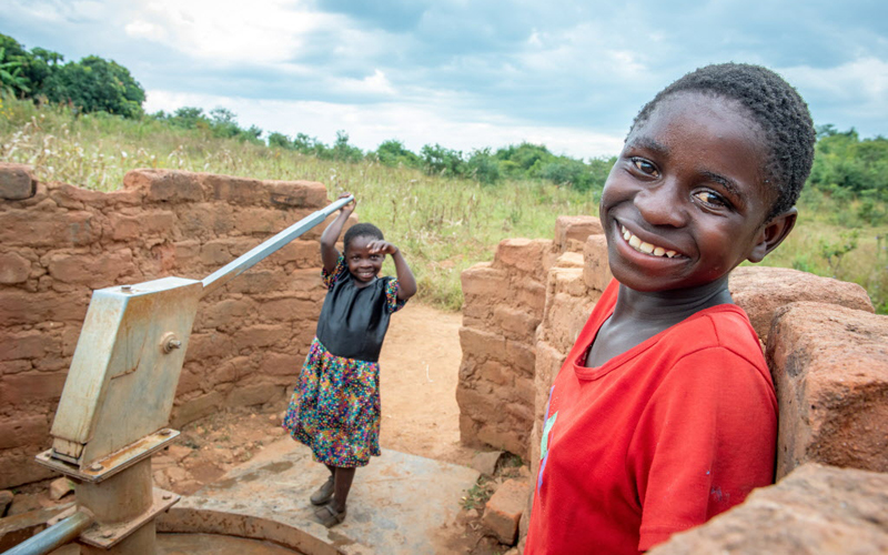 two girls at a water pump