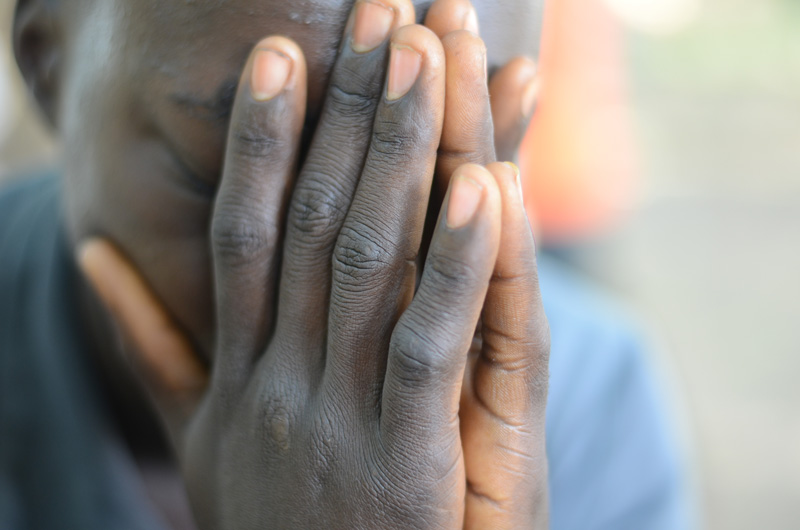 A young man leaning forward on his hands with his eyes closed.