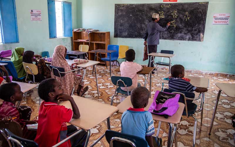 Un enseignant se tient debout devant une classe en train d’enseigner les mathématiques aux élèves.