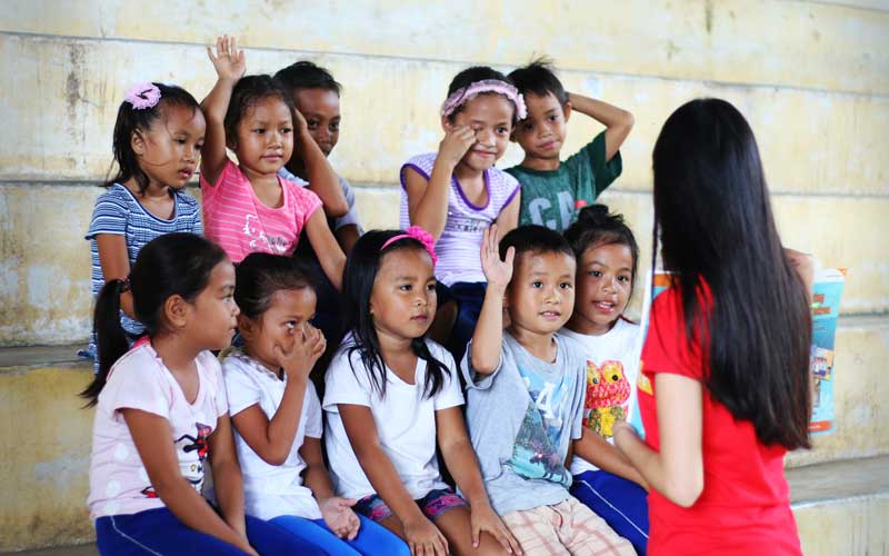 Une enseignante apprend à lire aux filles et aux garçons.