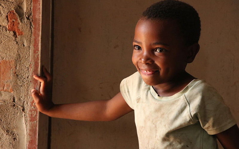 Une fillette zambienne sourit dans une entrée.