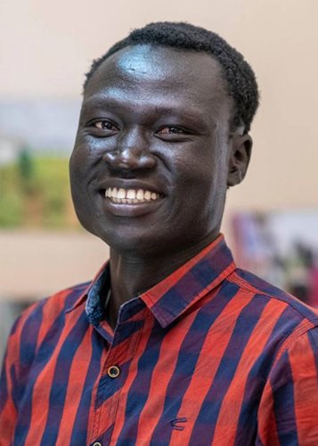 a young Sudanese man smiles at the camera