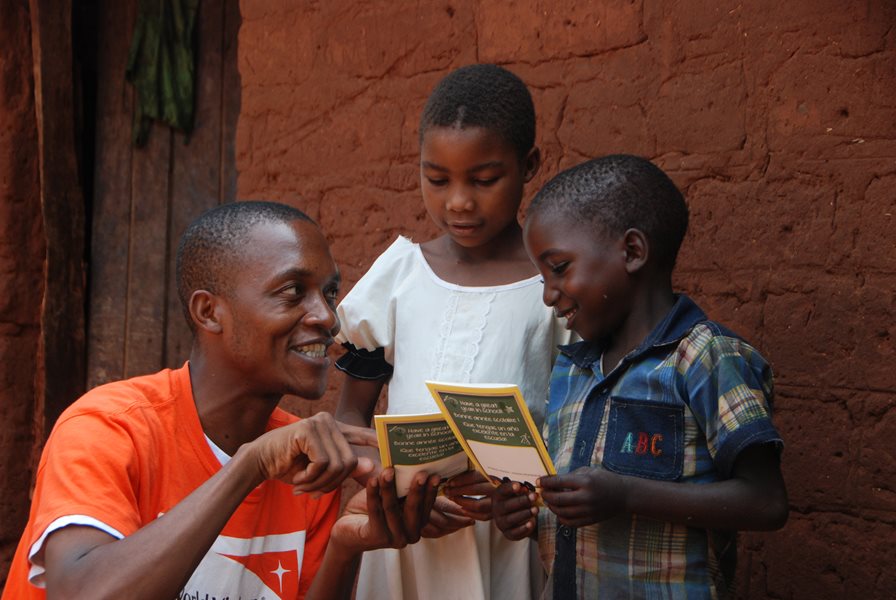 Un ambassadeur d'enfant lisant un pamphlet avec deux enfants.