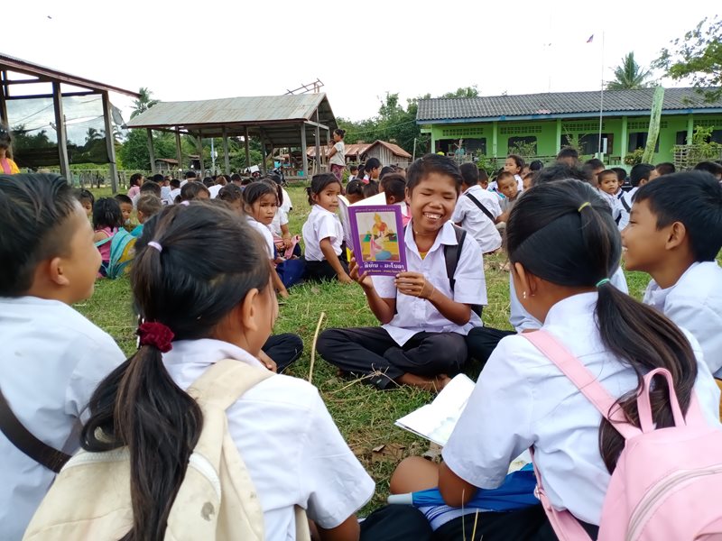 Students gather in a circle while reading a book.