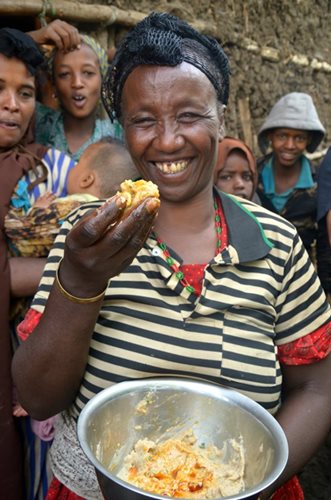 A smiling woman holds up maqua from a bowl, her friends behind her